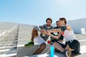 Gruppe junger Leute auf langer Betontreppe zeigen sich ihre Fitnesstracker Gruppe junger Leute auf langer Betontreppe zeigen sich ihre Fitnesstracker